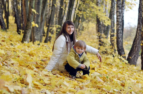 Feliz madre y bebé para un paseo en el parque de otoño se sentó en el y —  Fotos de Stock