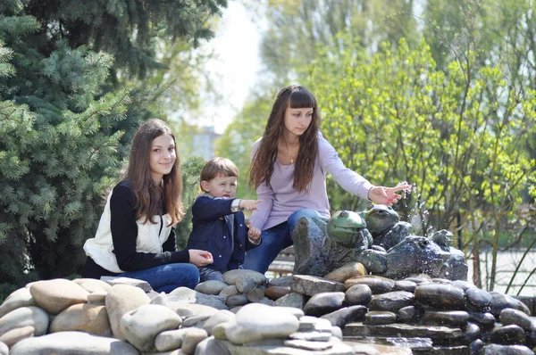 Hermosas chicas y bebé descansando en el parque cerca de la fuente —  Fotos de Stock