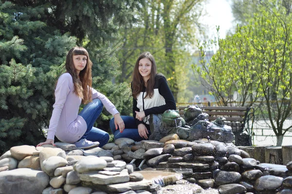 Schöne Mädchen ruhen sich in einem Park in der Nähe des Brunnens aus — Stockfoto