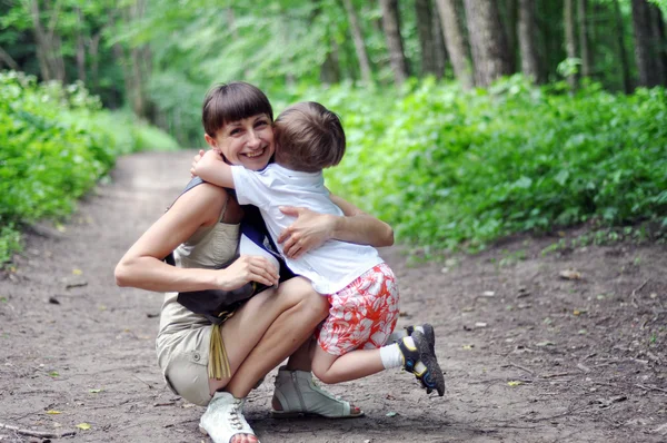 Kid embraces mother on walk in park — Stock Photo, Image