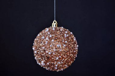 Siyah arka planda incileri olan altın bir Noel balosu. Noel tebrik kartı.