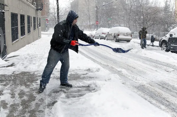 Een man die sneeuw schept — Stockfoto