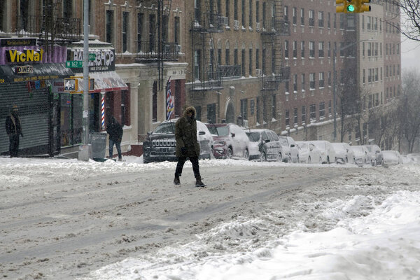 BRONX, NEW YORK, USA - January 29, 2022: Man crossing street during snow fall.