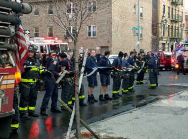 BRONX, New York, ABD - 24 Şubat 2022: İtfaiyeci yangına yanıt verdikten sonra hortumu kamyona geri sardı.