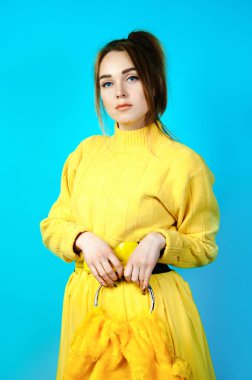 Sarı elbiseli güzel bir kadın elinde bir çantayla. mavi arkaplan