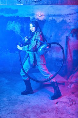 Terk edilmiş bir binada neon ışığı altında solunum cihazı olan bir kız. konsept