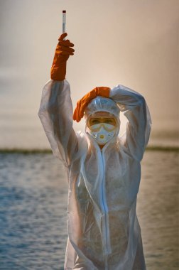 Koruma giysisi ve maskesi olan bir uzman tarafından suyu kontrol ediliyor.