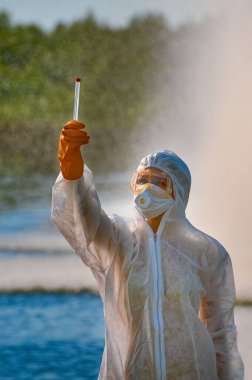 Koruma giysisi ve maskesi olan bir uzman tarafından suyu kontrol ediliyor.