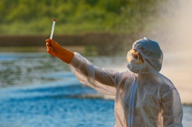 Koruma giysisi ve maskesi olan bir uzman tarafından suyu kontrol ediliyor.