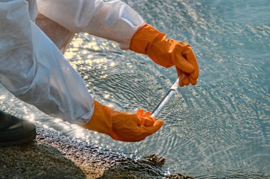 Koruma giysisi ve maskesi olan bir uzman tarafından suyu kontrol ediliyor.