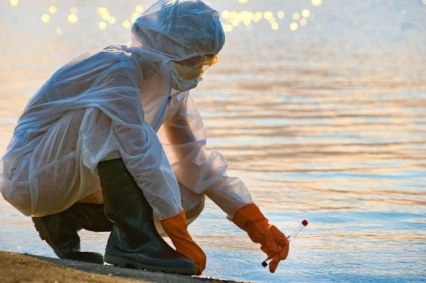 Koruma giysisi ve maskesi olan bir uzman tarafından suyu kontrol ediliyor.