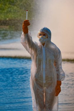 Koruma giysisi ve maskesi olan bir uzman tarafından suyu kontrol ediliyor.