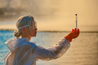 Koruma giysisi ve maskesi olan bir uzman tarafından suyu kontrol ediliyor.