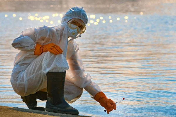 Koruma giysisi ve maskesi olan bir uzman tarafından suyu kontrol ediliyor.