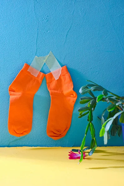 Πορτοκαλί Καθαρές Κάλτσες Κρέμονται Έναν Μπλε Τοίχο Στο Κίτρινο Τραπέζι — Φωτογραφία Αρχείου