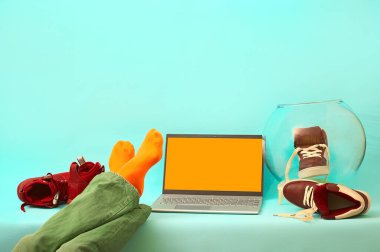 Adam bacakları masada dinleniyor. Mavi arka planda gümüş dizüstü bilgisayar