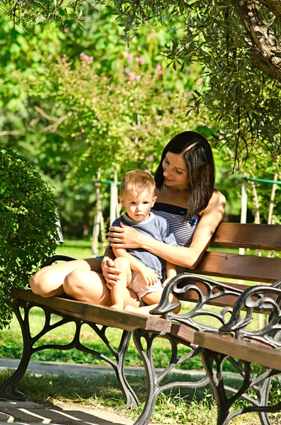Mama cu un fiu stă pe o bancă într-un parc — Fotografie, imagine de stoc