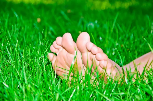 Womanish benen zijn in een groene gras — Stockfoto