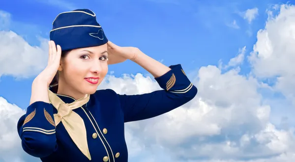 Hermosa azafata sonriente en uniforme sobre un cielo de fondo — Foto de Stock