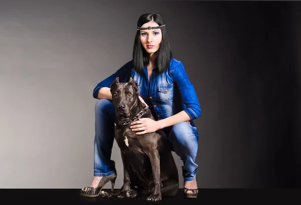 Красивая женщина в джинсах сидит рядом с собакой — стоковое фото