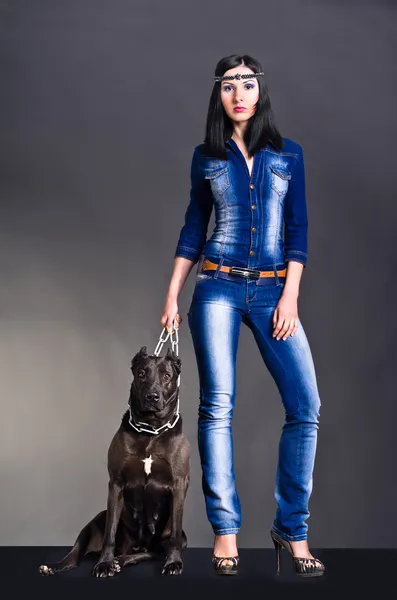 Mooie jonge vrouw in jeans kleding permanent naast een hond — Stockfoto