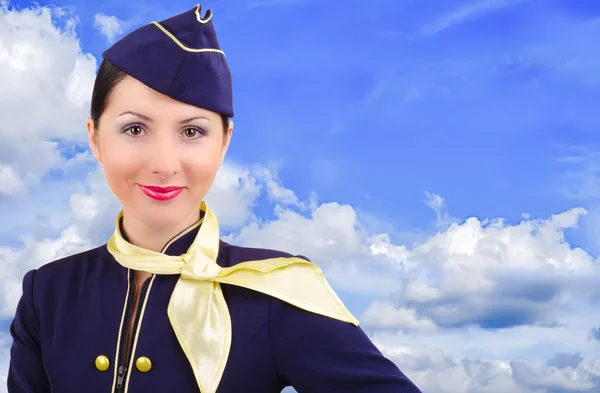 Beautiful smiling stewardess on a background sky — Stock Photo, Image