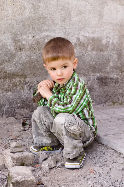벽의 배경에 그의 손에 있는 망치를 가진 귀여운 어린 소년 — 스톡 사진