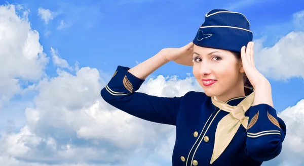 Azafata sonriente en uniforme sobre un cielo de fondo — Foto de Stock