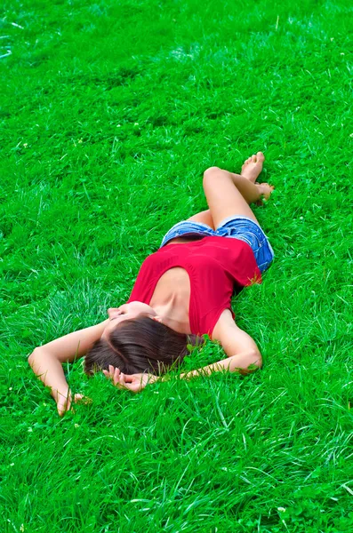 Beautiful young slim woman relaxing lying on the grass — Stock Photo, Image