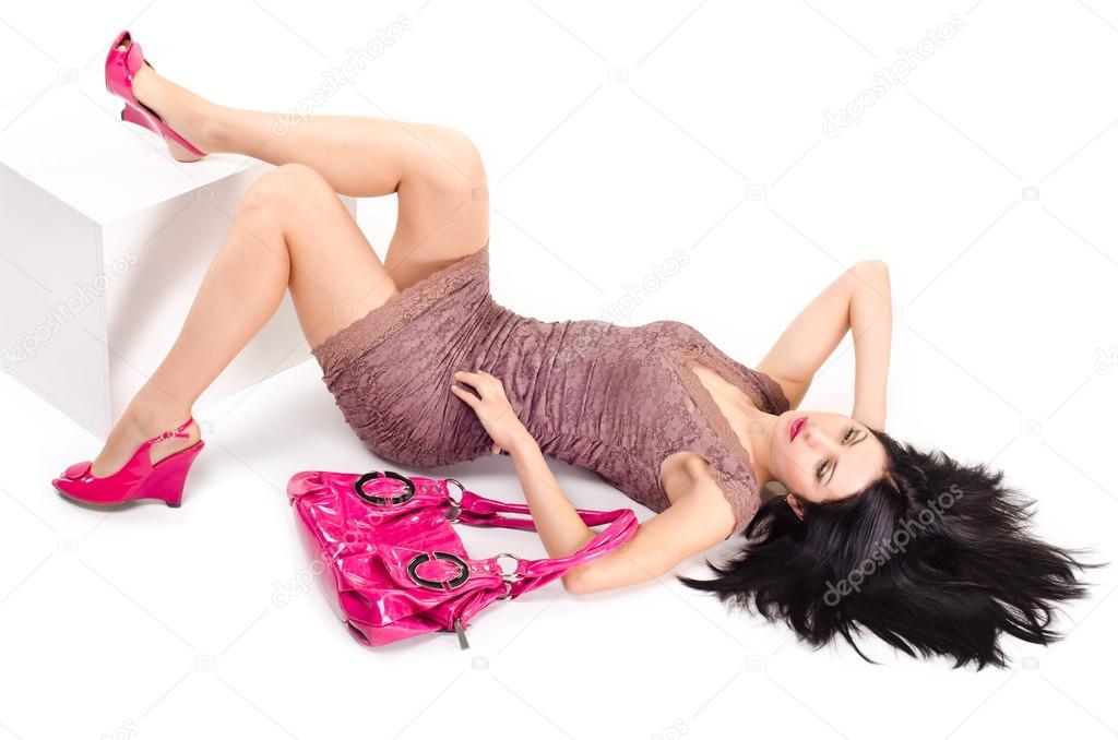 Girl lying on the floor with disheveled hair and keeps on hand bag