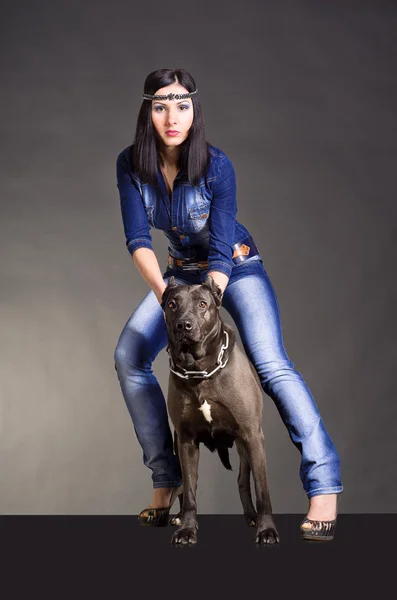 Hermosa joven con ropa vaquera de pie junto a un pitbulls —  Fotos de Stock