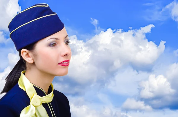 Portrait of a beautiful young stewardess in profile on the sky background — Stock Photo, Image