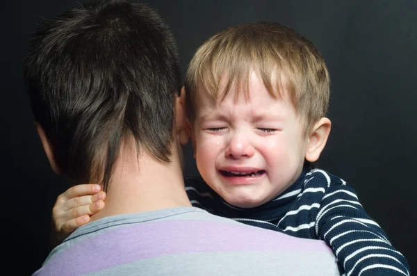 Плачущий ребенок на руках своего отца — стоковое фото