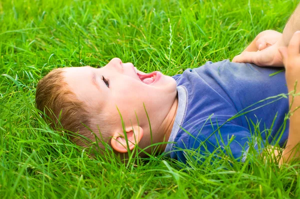 Retrato de lindo niño riendo acostado en la hierba — Foto de Stock