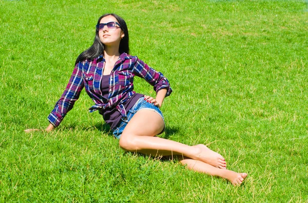 Beautiful slim young woman sitting on the lawn — Stock Photo, Image