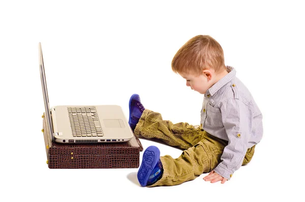 Bonito menino sentado diante de um laptop — Fotografia de Stock