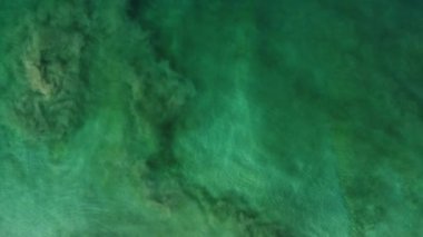Video için soyut arkaplan. Yukarıdan okyanus manzarası, deniz yatağı ve dalgaların altındaki kum. Rüzgardan gelen su hareketi ve sörfün sualtı alanı üzerindeki etkisi. Hava 4k.