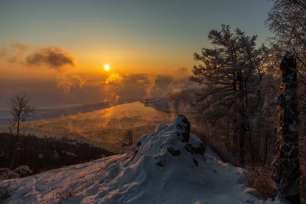 Lake Baikal - Chersky Stone. Winter sunset and steam over the water of the Angara river