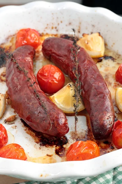 Baked pork or beef sausages with cherry tomatoes, thyme and lemon — Stock Photo, Image