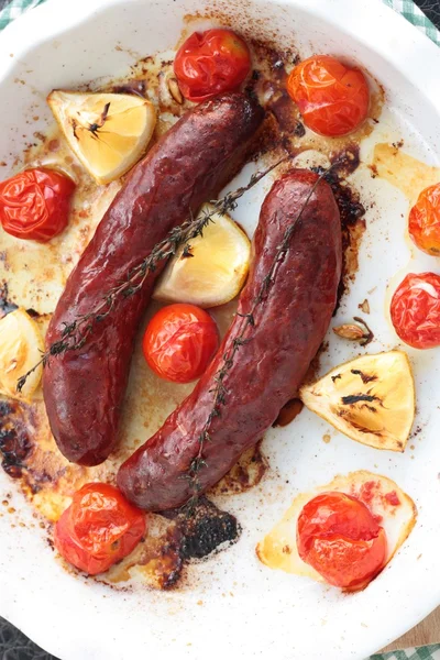 Baked pork or beef sausages with cherry tomatoes, thyme and lemon — Stock Photo, Image