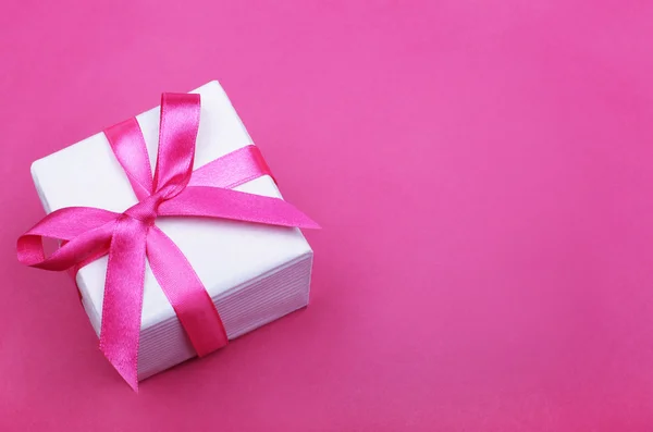 Gift box with pink ribbon on pink background — Stock Photo, Image