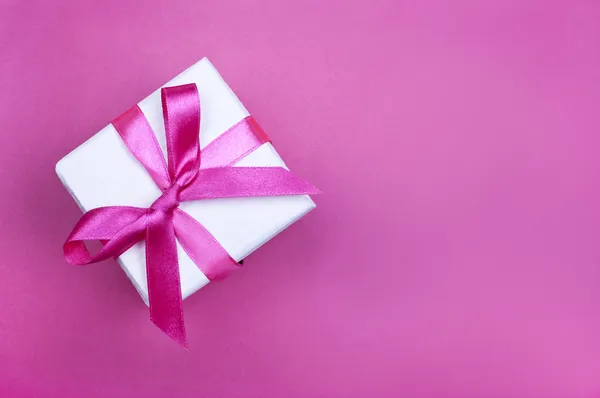 Geschenkbox mit rosa Schleife auf rosa Hintergrund — Stockfoto