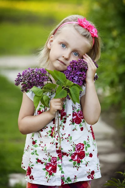 Маленькая девочка с лиловым букетом в саду — стоковое фото