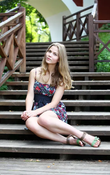 Beautiful young girl sitting at ladder steps in the park Stock Picture