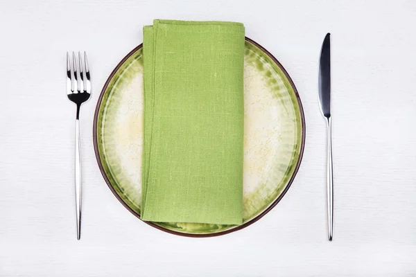 Serving - fork, knife and green napkin on green plate, top view Stock Picture