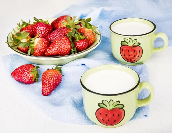 Fresas en un plato y leche en tazas de cerámica en servilleta azul —  Fotos de Stock