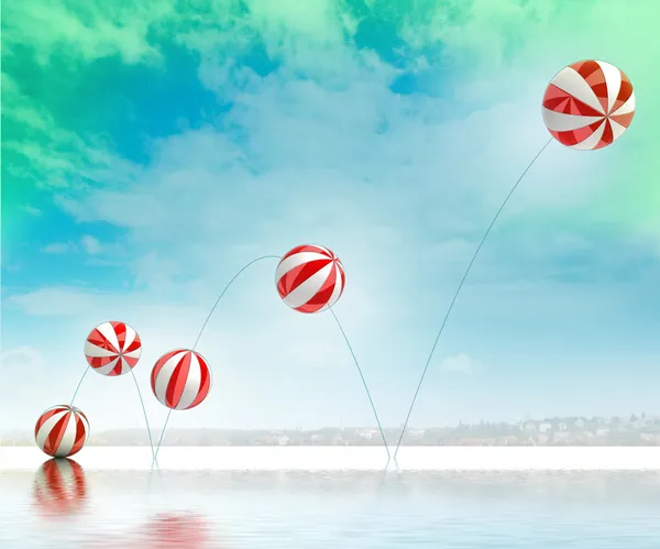 Five jumping white red striped inflatable balls on beach with sea — Stock Photo, Image