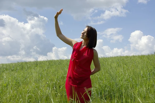 Hermosa mujer en campo de hierba verde y cielo nublado — Foto de Stock