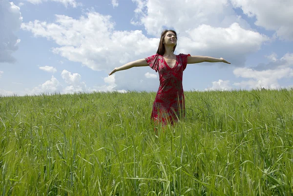 Mulher bonita no campo de grama verde e céu nuvem — Fotografia de Stock