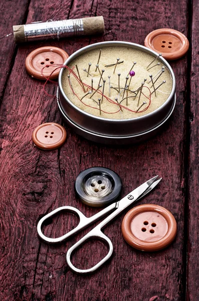 Schere und Faden auf den bemalten roten Tellern — Stockfoto